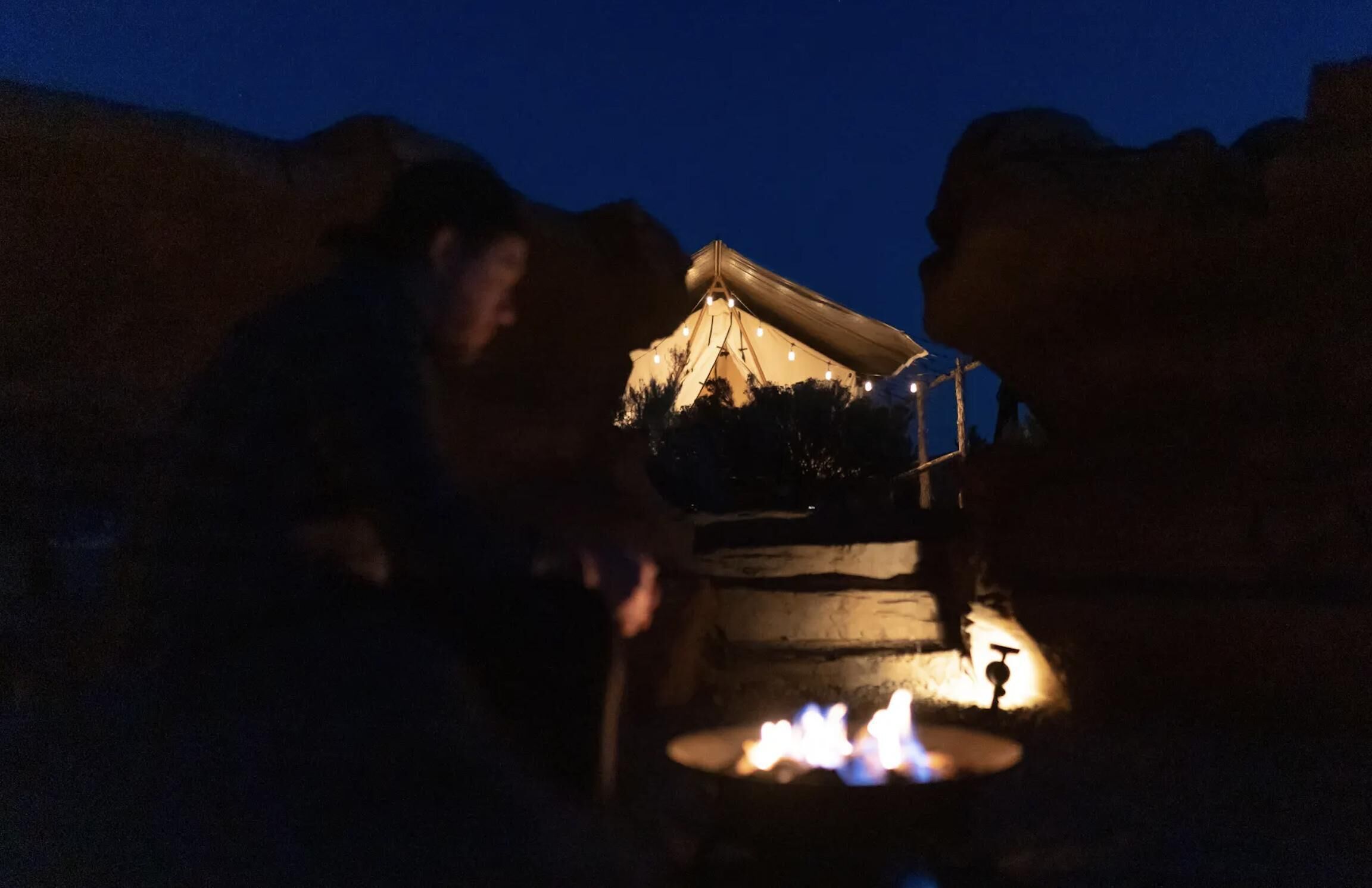 A person sitting by a campfire at night.