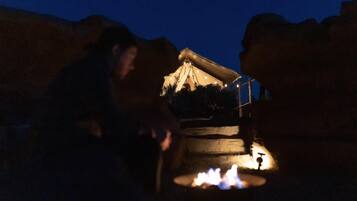 A person sitting by a campfire at night.