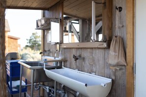Un baño rústico con pared de madera, un lavabo blanco y un espejo.