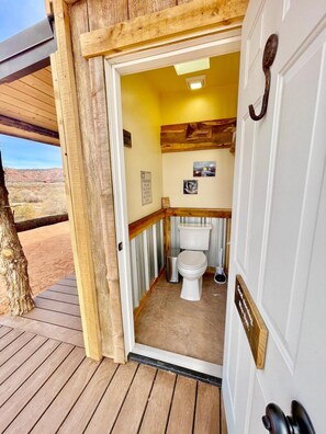 A wooden deck leading to a compact bathroom with a toilet, a small sink, and a mirror. - Glamp Tent b/w Zion & Bryce, Outdoor Shower & Wifi (Fredonia)