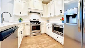 A modern kitchen with white cabinets, stainless steel appliances, and a wooden floor. - The Oaks, 3BR Escape by Velvet Ditch Villas (Oxford)