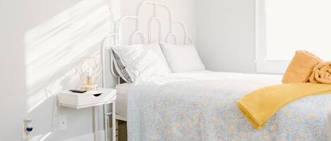 A neatly arranged bedroom with a bed, bedside table, and a small window.