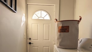 A laundry room with a door, a washing machine, and a laundry basket.