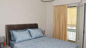 Een slaapkamer met een bed, nachtkastje, lamp en een raam met gordijnen.