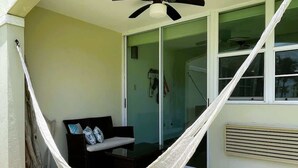 Una cadira espanyola a un pati amb un ventilador de sostre, una porta corredissa de vidre i una petita zona d'aixetes amb coixins.