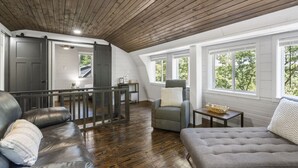 A spacious loft-style room with a high ceiling, wooden beams, and large windows offering views of greenery. - No Regrets at the North Fork River (Dawt)