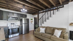A modern kitchen with stainless steel appliances, a wooden ceiling, and a cozy living area with a sofa and fireplace. - No Regrets at the North Fork River (Dawt)
