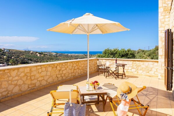 Una terrazza con tavolo, sedie e ombrellone, affacciata su un paesaggio suggestivo.