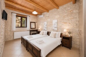 Ein Schlafzimmer mit zwei Betten, einem Fernseher, einem Kamin und Steinwänden.