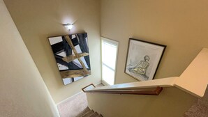 Una escalera con barandilla, un cuadro abstracto enmarcado y otro cuadro en la pared.