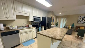 Una cocina moderna con armarios blancos, microondas integrado y una isla grande con encimera de granito.