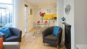A modern living room with two sofas, a dining area with a table and chairs, and a kitchen in the background. - Charming Tower Bridge House (London)