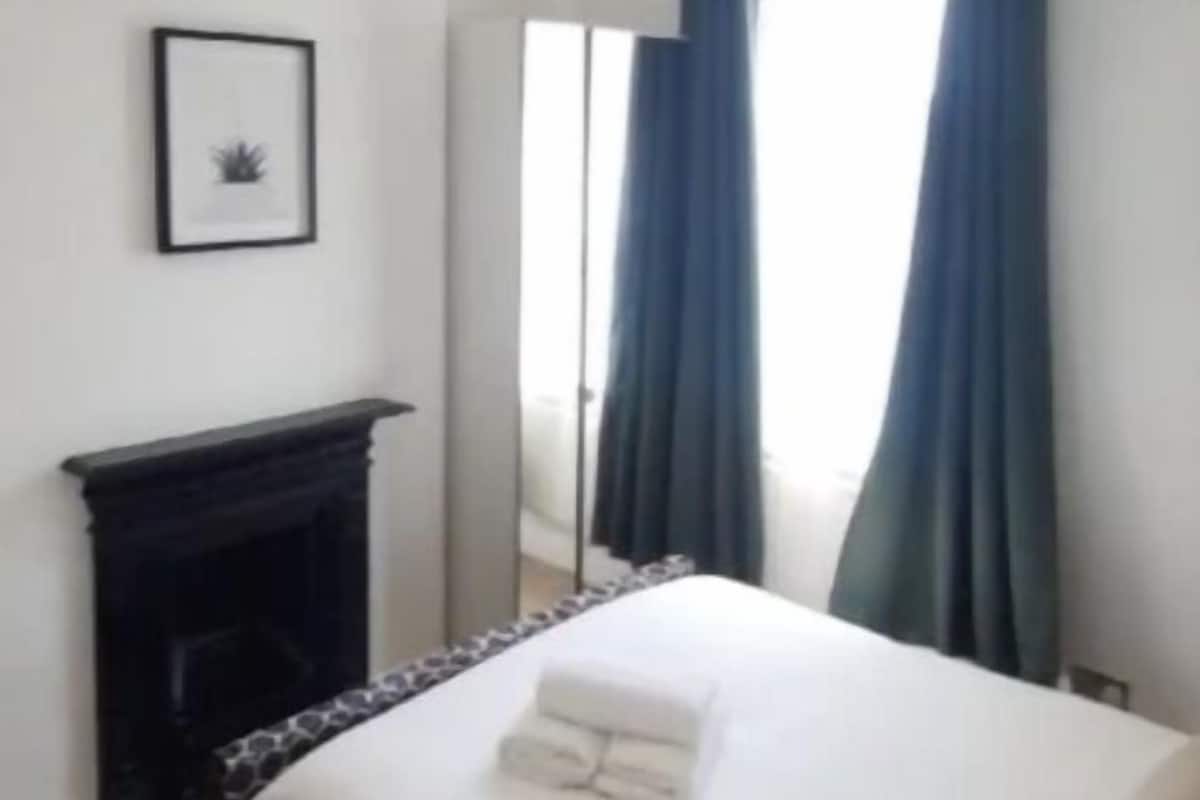 A bedroom with a bed, a fireplace, and a window with curtains.