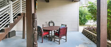 Un espacio al aire libre cubierto con una mesa y sillas de madera, una escalera y vistas al verdor.