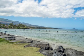 A coastal area with rocky shores, clear water, and a distant mountain. - Island Surf 510A by Maui Rental Group (Kihei)