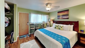 A hotel room with a bed, a nightstand, a desk with a chair, a wardrobe, and a window with curtains. - Island Surf 510A by Maui Rental Group (Kihei)