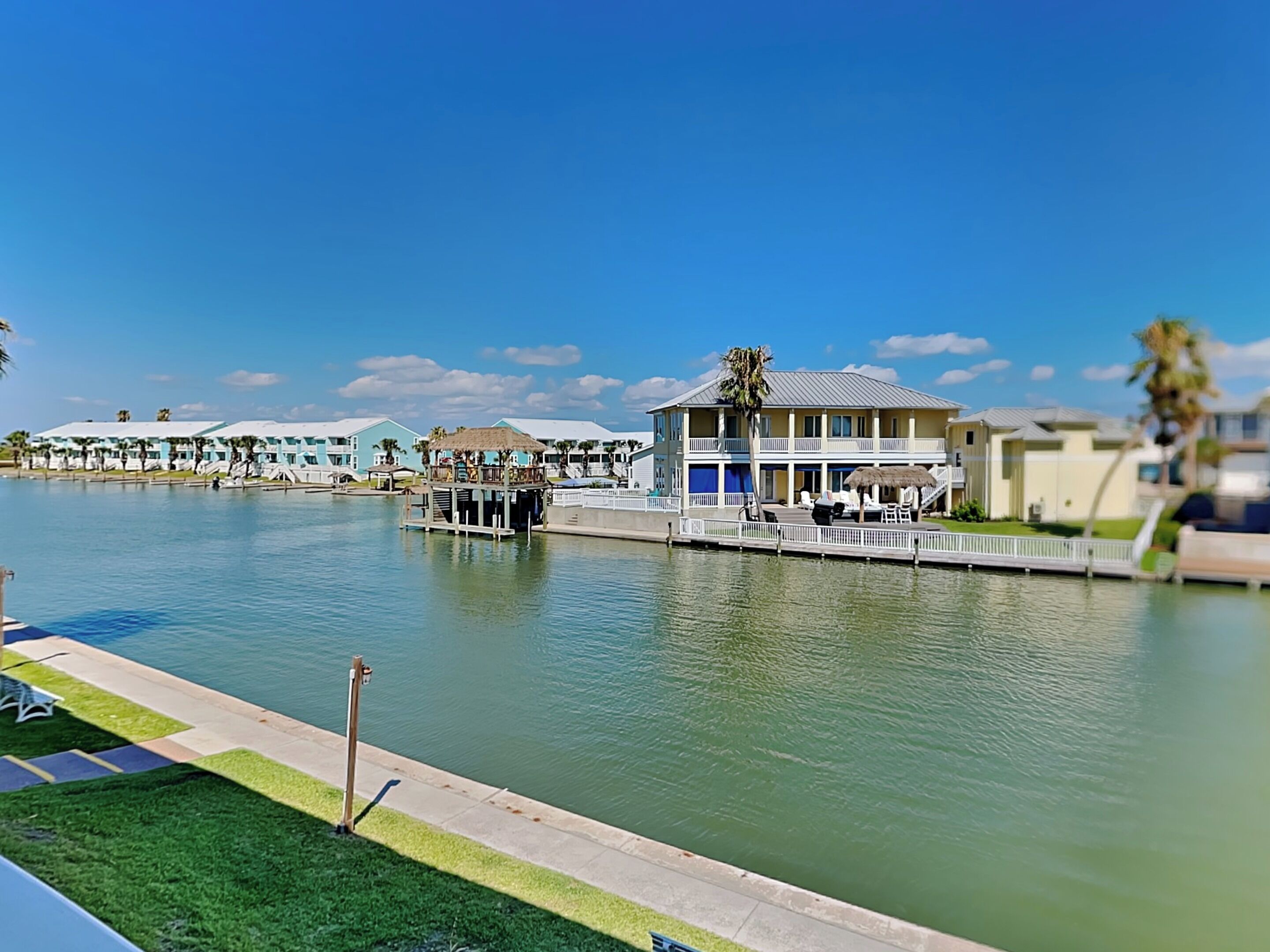 A waterfront hotel with multiple buildings, a dock, and a clear blue sky.