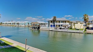 Un hôtel situé au bord de l’eau, composé de plusieurs bâtiments, doté d’un quai et offrant une vue sur un ciel bleu azur.