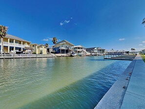 Une propriété située au bord de l’eau, comprenant plusieurs bâtiments, un quai et un ciel d’un bleu éclatant.