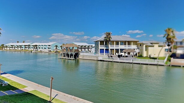 Ein Hotel am Wasser mit mehreren Gebäuden, einem Steg und wolkenlosem, blauem Himmel.