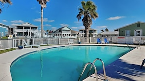 Ein Schwimmbecken mit weißem Zaun, Palmen und ein Gebäude mit dem Schild 'Lakeside Beach Resort'.