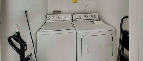 Een wasruimte met twee witte wasmachines en een droogrek.
