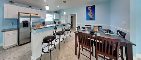 Una cocina moderna con una isla central, taburetes de bar y una mesa de comedor con sillas.
