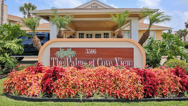 A sign for The Palm at Cove View, featuring a building with a beige facade and a number 3506. - Glowing Fun by Ryson Vacation Rentals (Galveston)