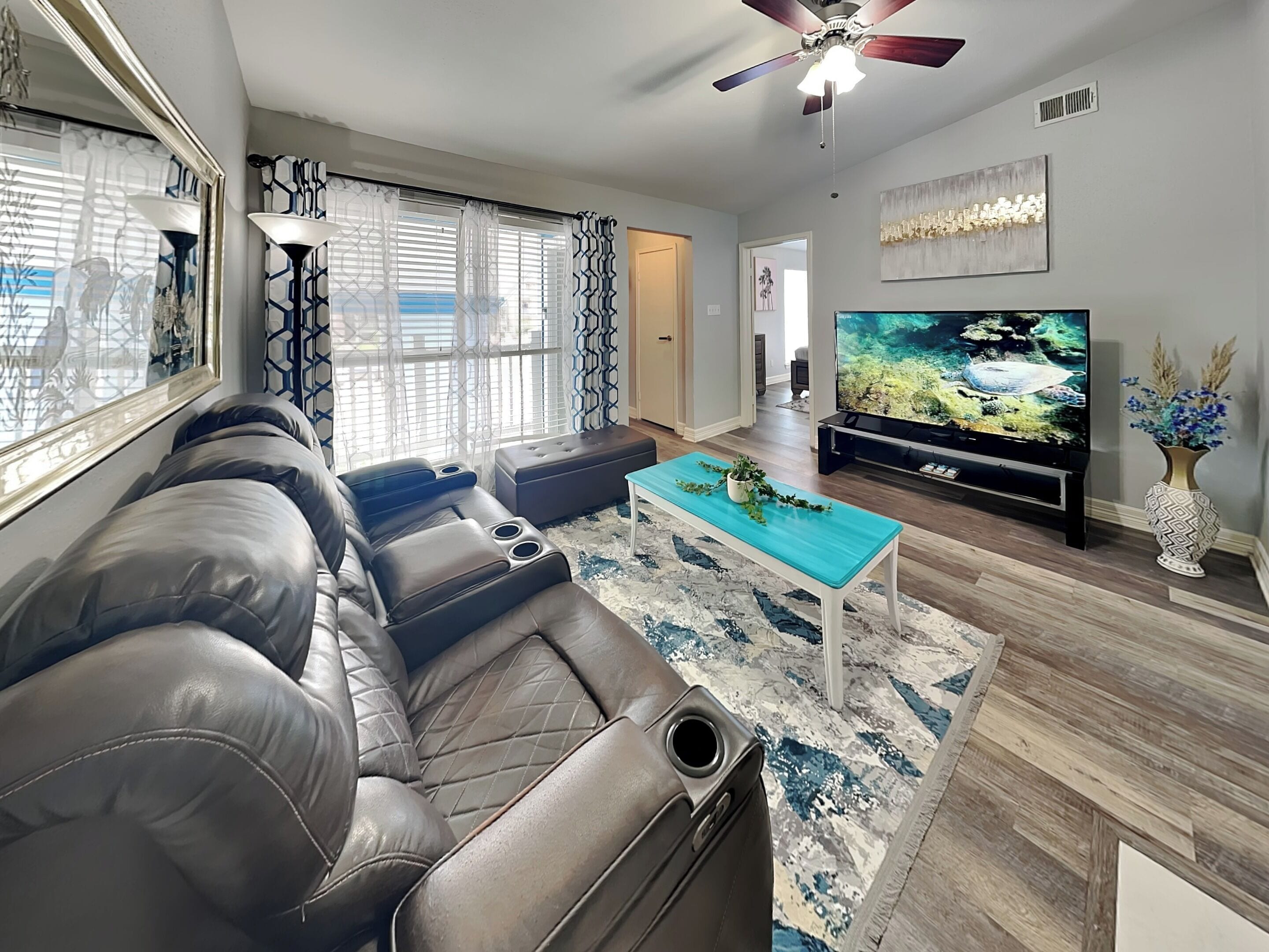 A modern living room with a leather sofa, a TV, and a decorative plant.