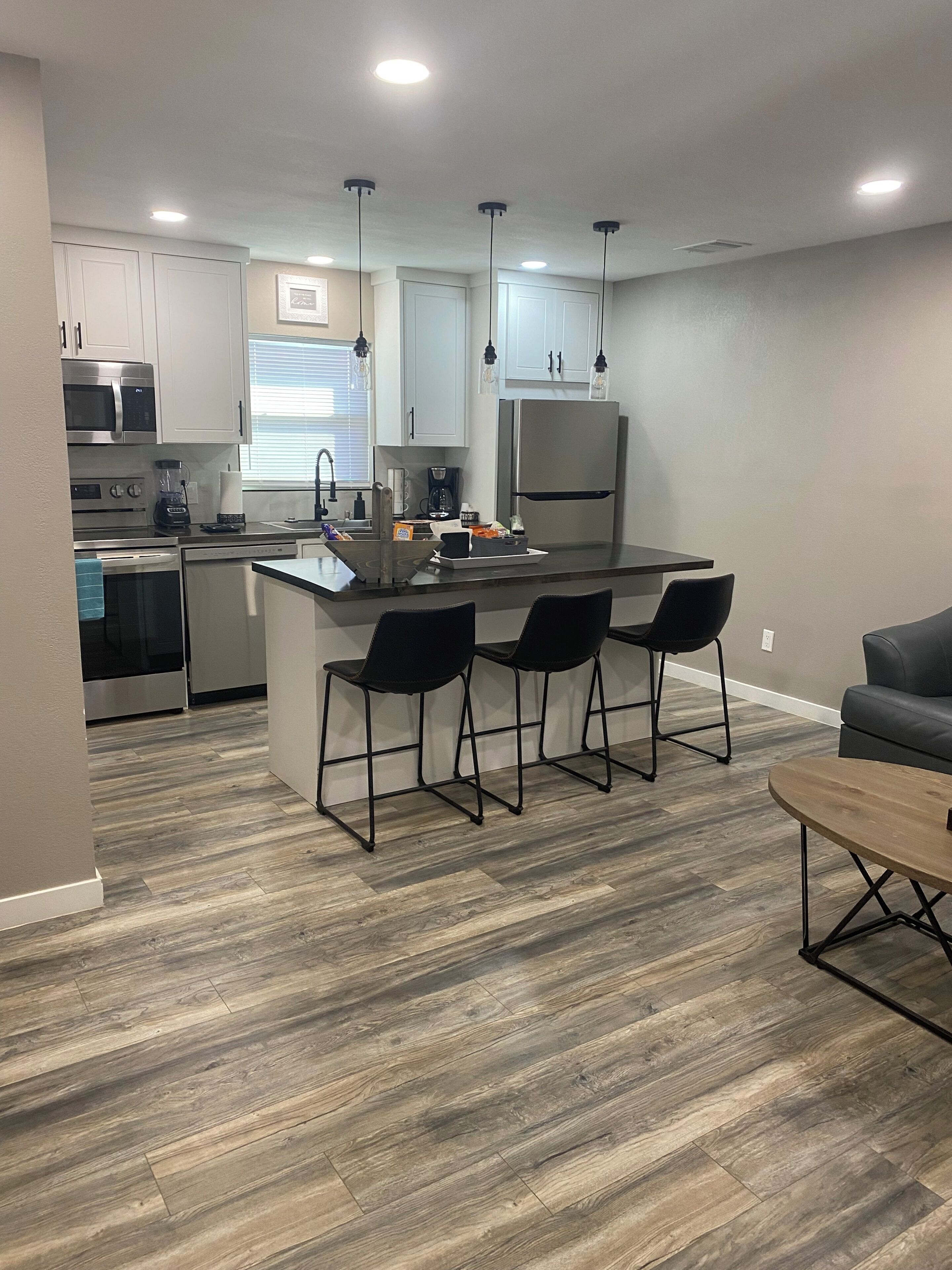 A modern kitchen with a central island, bar stools, and a dining area with a table and chairs.