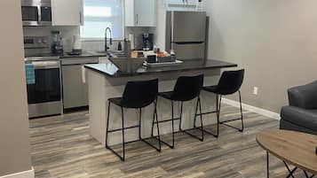 Una cocina moderna con una isla central, taburetes de bar y un comedor con mesa y sillas.