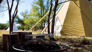 Un camping con tiendas de campaña y un hornillo portátil.