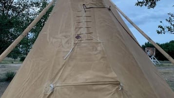 Una gran tienda tipi cónica con una estructura robusta y cubierta de lona.