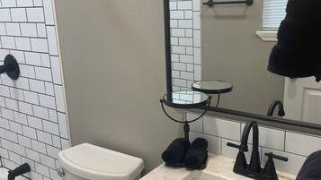 A bathroom with a white toilet, a sink with a mirror above it, and a towel rack.