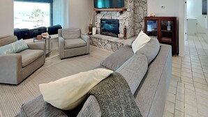 Ein modernes Wohnzimmer mit Kamin aus Stein, einem großen Flachbildfernseher und einer gemütlichen Sitzecke.