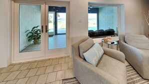Ein modernes Wohnzimmer mit einem beigen Sofa, einer Glastür, die auf einen Balkon führt, und Blick ins Freie.