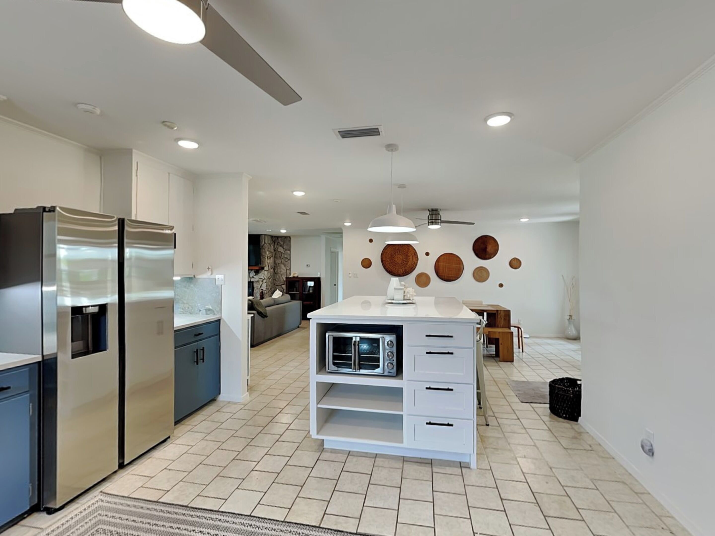 Una cocina moderna con electrodomésticos de acero inoxidable, una isla blanca con microondas y un comedor con mesa y sillas de madera.