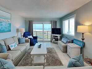 A living room with a sofa, armchairs, a coffee table, a TV, and a sign reading "BEACH HOUSE". - Sea 4 Ever by Distinctive Beach Rentals (Flagler Beach)