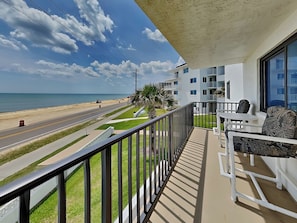 A balcony with a view of the beach and ocean, a white building with balconies, and a clear sky. - Sea 4 Ever by Distinctive Beach Rentals (Flagler Beach)
