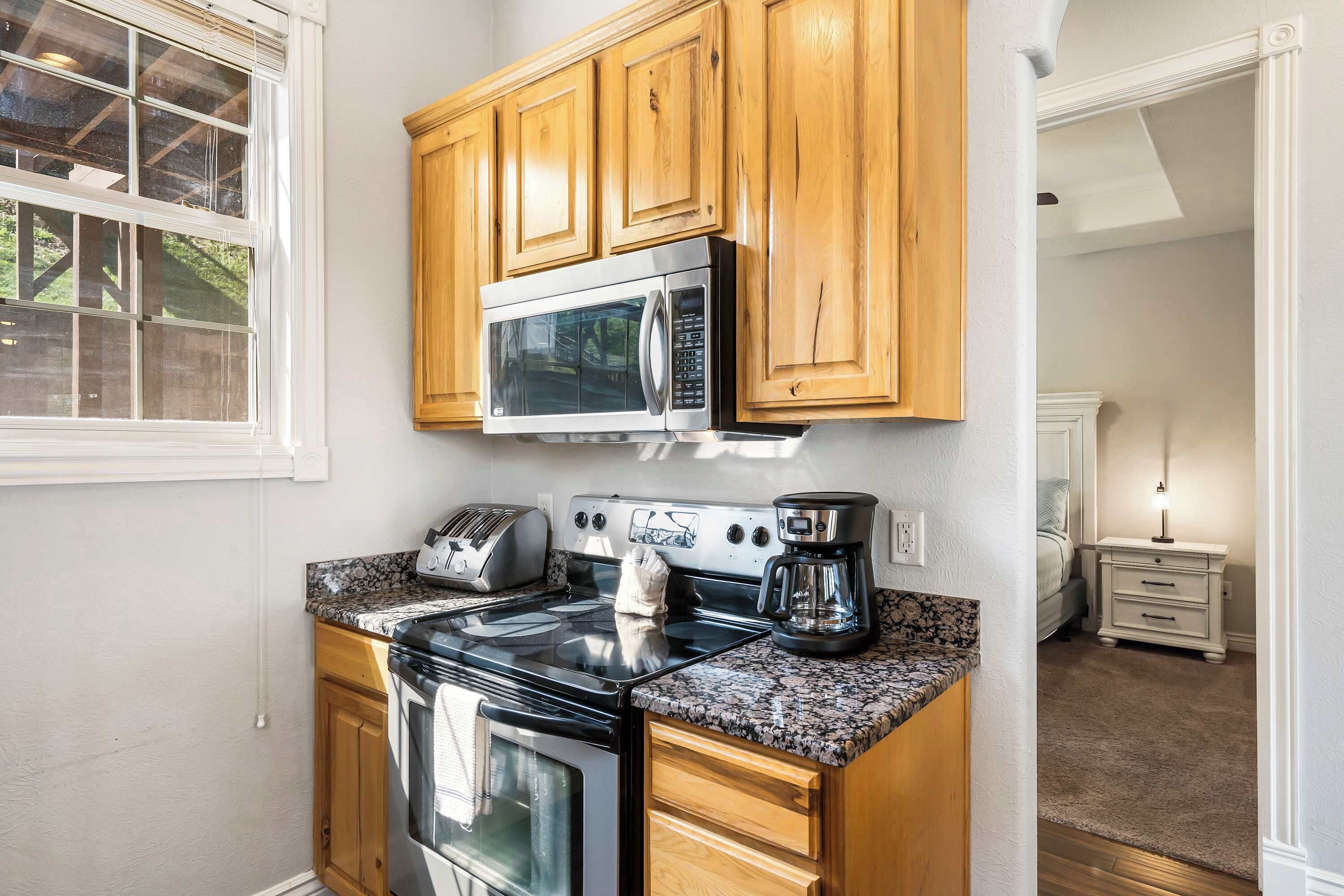 A kitchen with wooden cabinets, a stainless steel microwave, a toaster, and a coffee maker.
