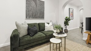 Un salon moderne avec un canapé vert, une table basse ronde et un téléviseur à écran plat.