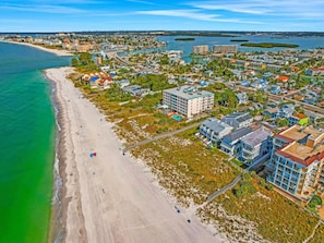 An aerial view of a coastal town with a sandy beach, residential buildings, and a marina. - Sunshine Lane by Distinctive Beach Rentals (Treasure Island)