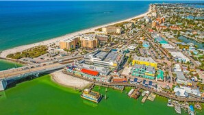 An aerial view of a coastal city with a prominent bridge, marina, and dense urban area with buildings and roads. - Sunshine Lane by Distinctive Beach Rentals (Treasure Island)