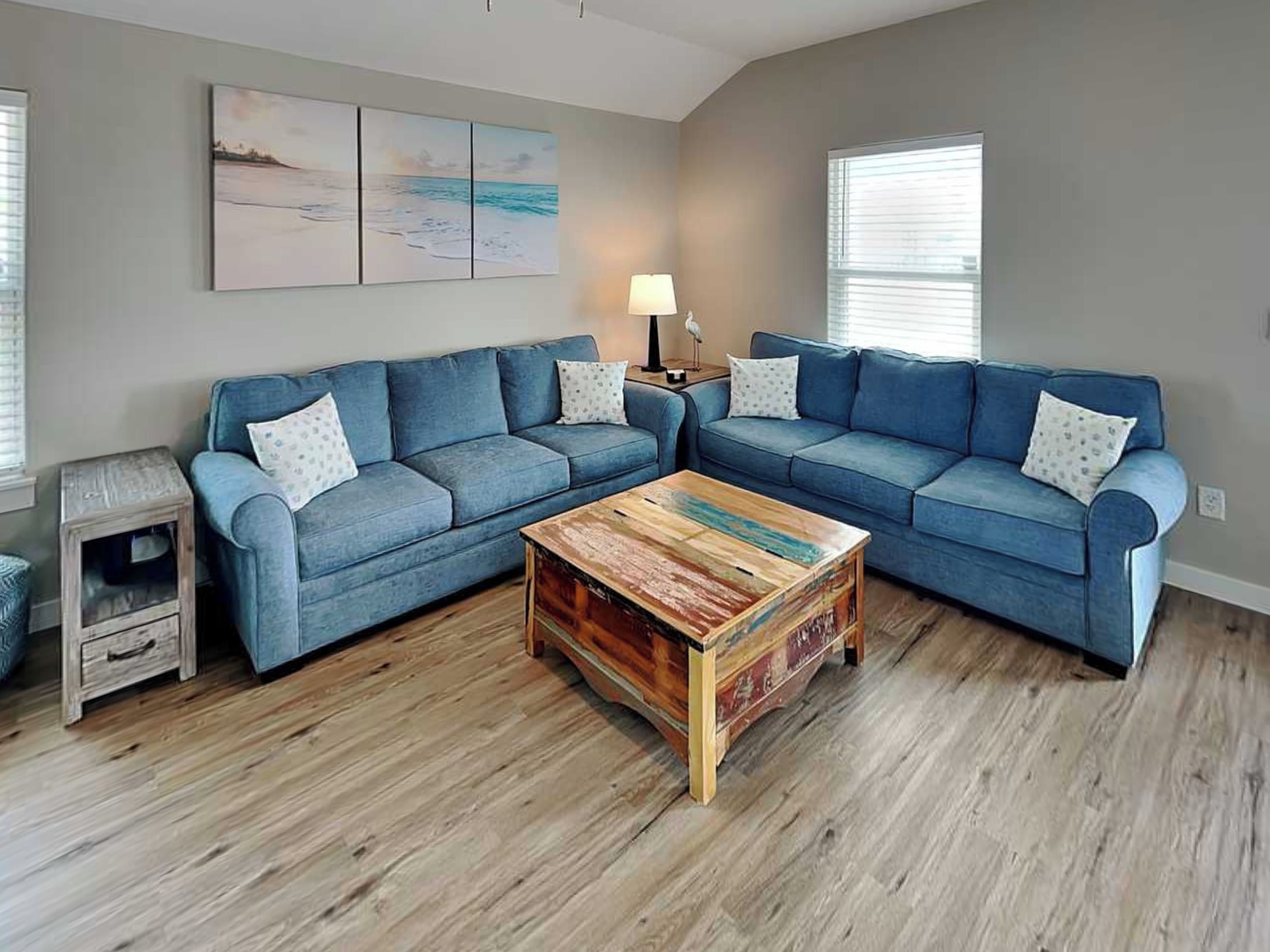 A living room with a sectional sofa, a coffee table, and a painting on the wall.