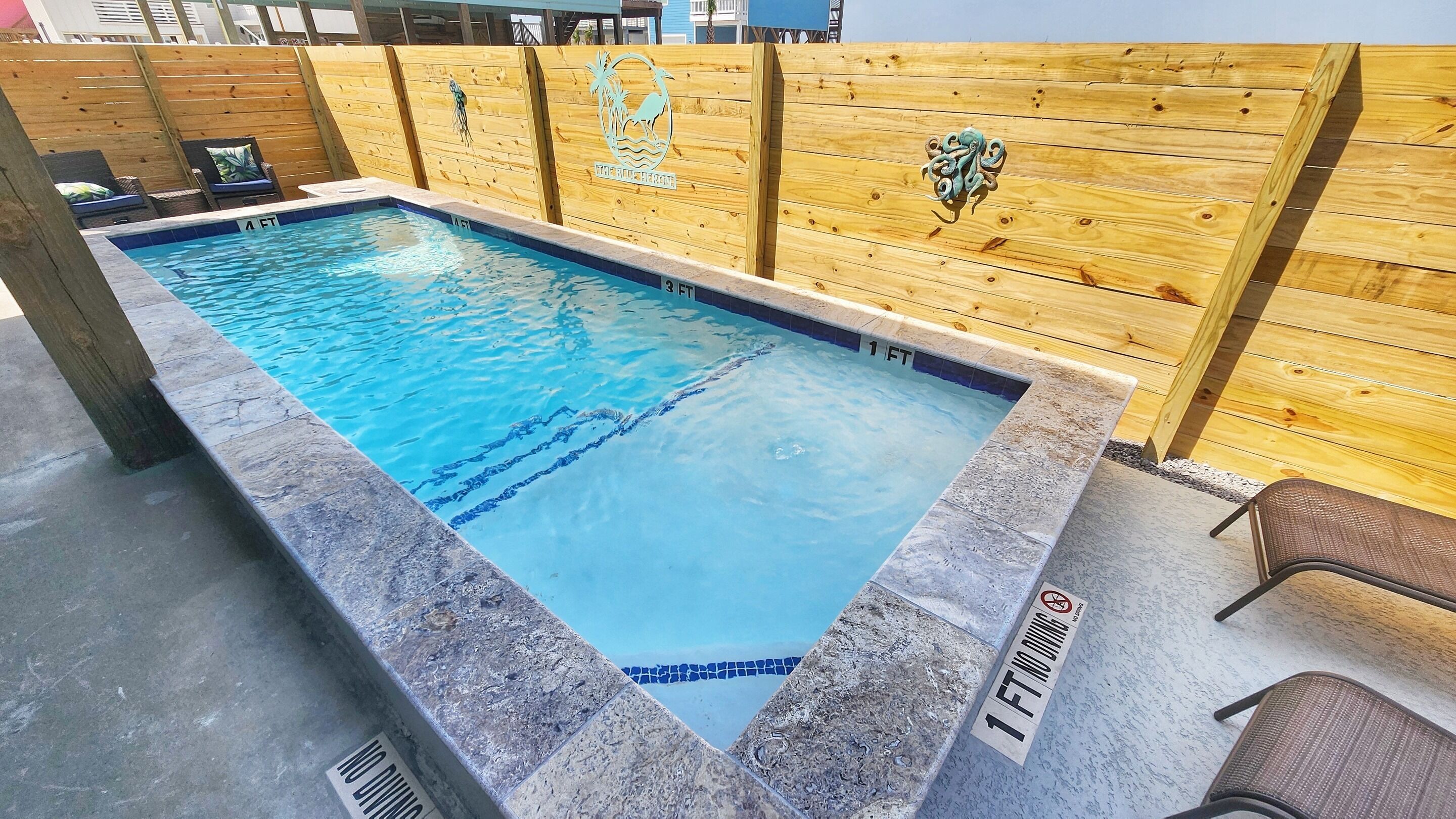 A rectangular pool with a wooden fence and a sign indicating a depth of 3 feet.
