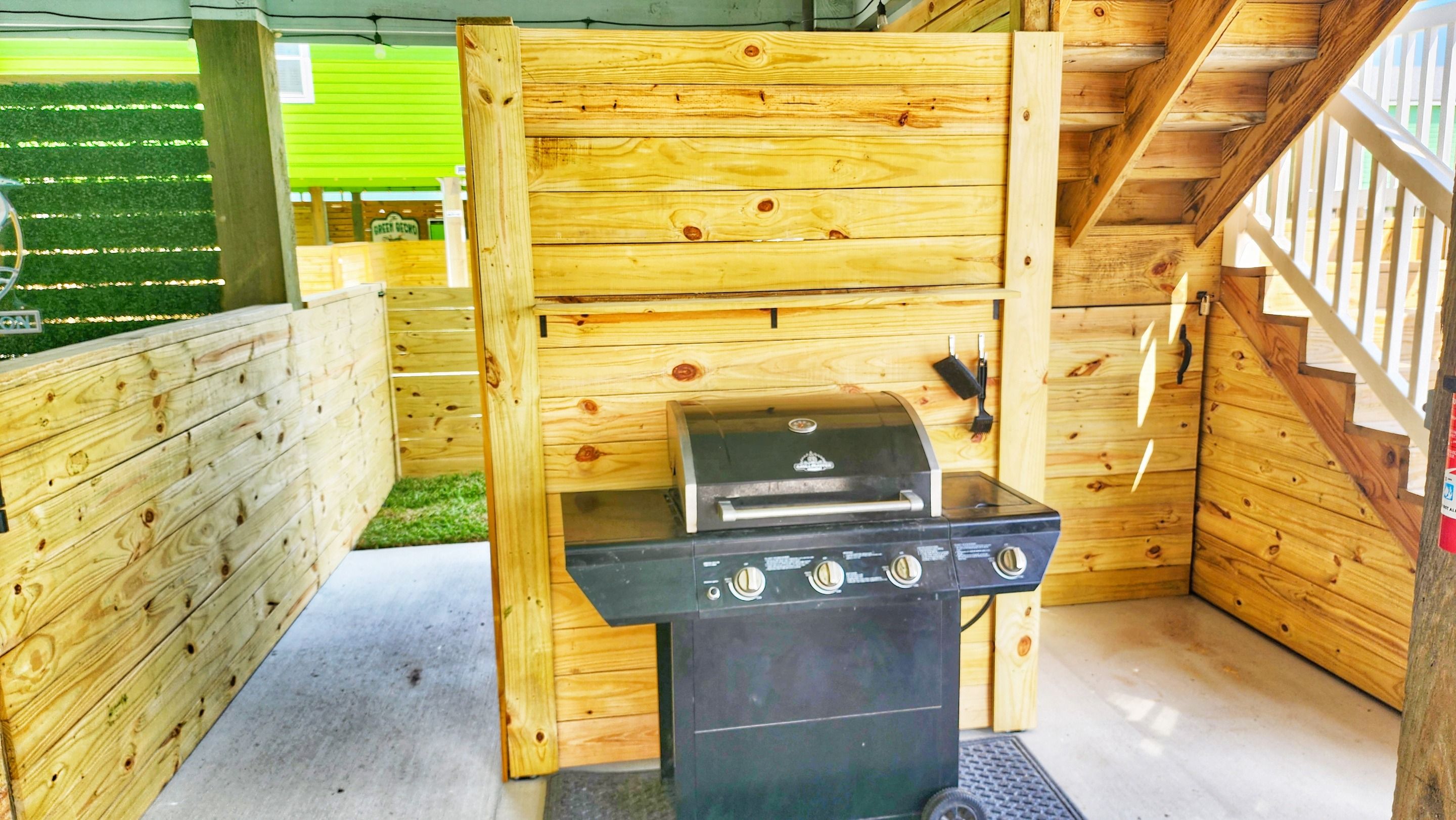 A wooden outdoor grill area with a concrete floor and a wooden fence.