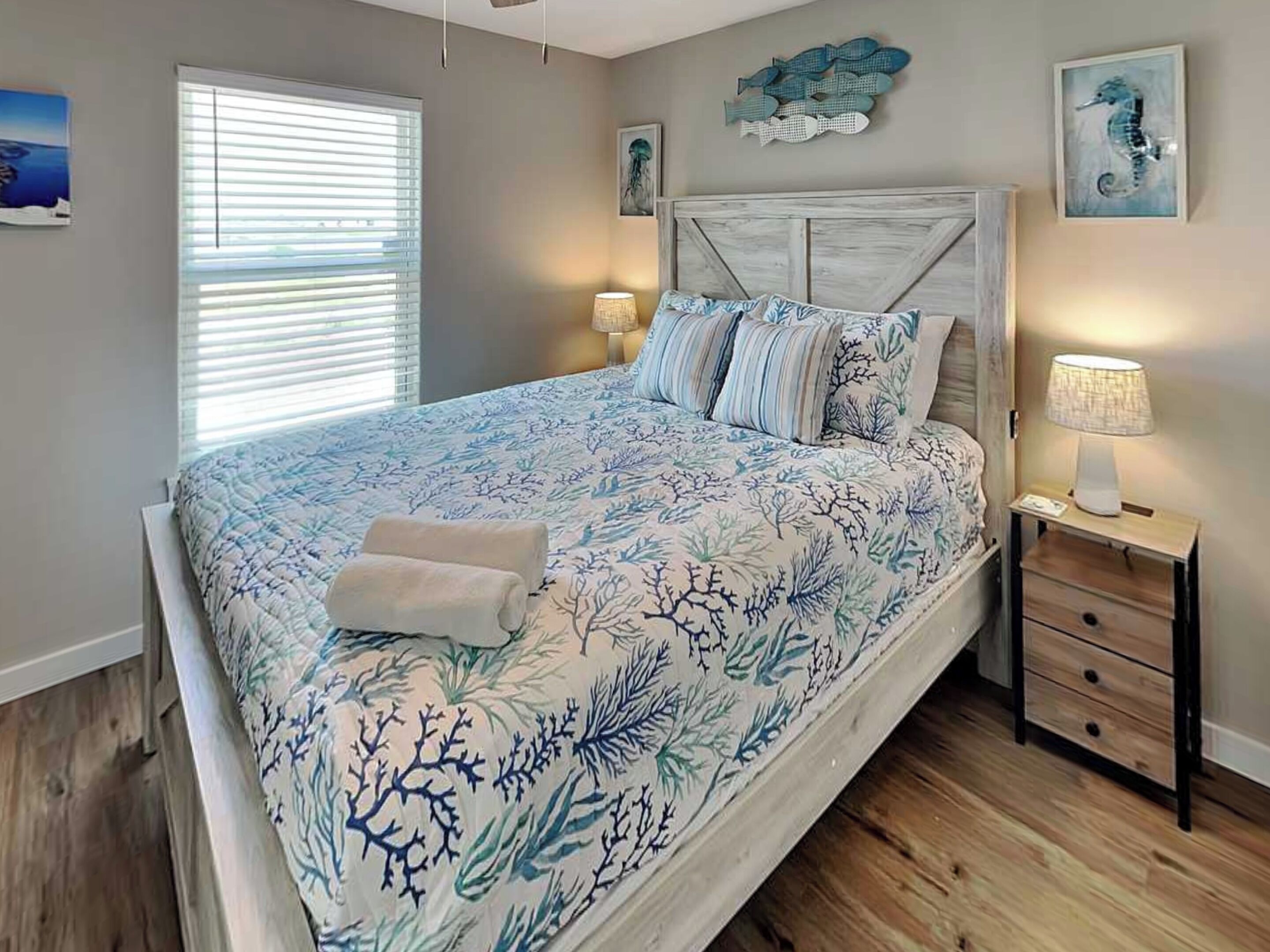 A bedroom with a bed, a nightstand, a lamp, and wall art.