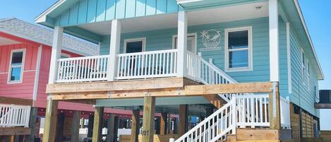 A two-story house with a balcony, wooden deck, and a staircase leading to the upper floor.