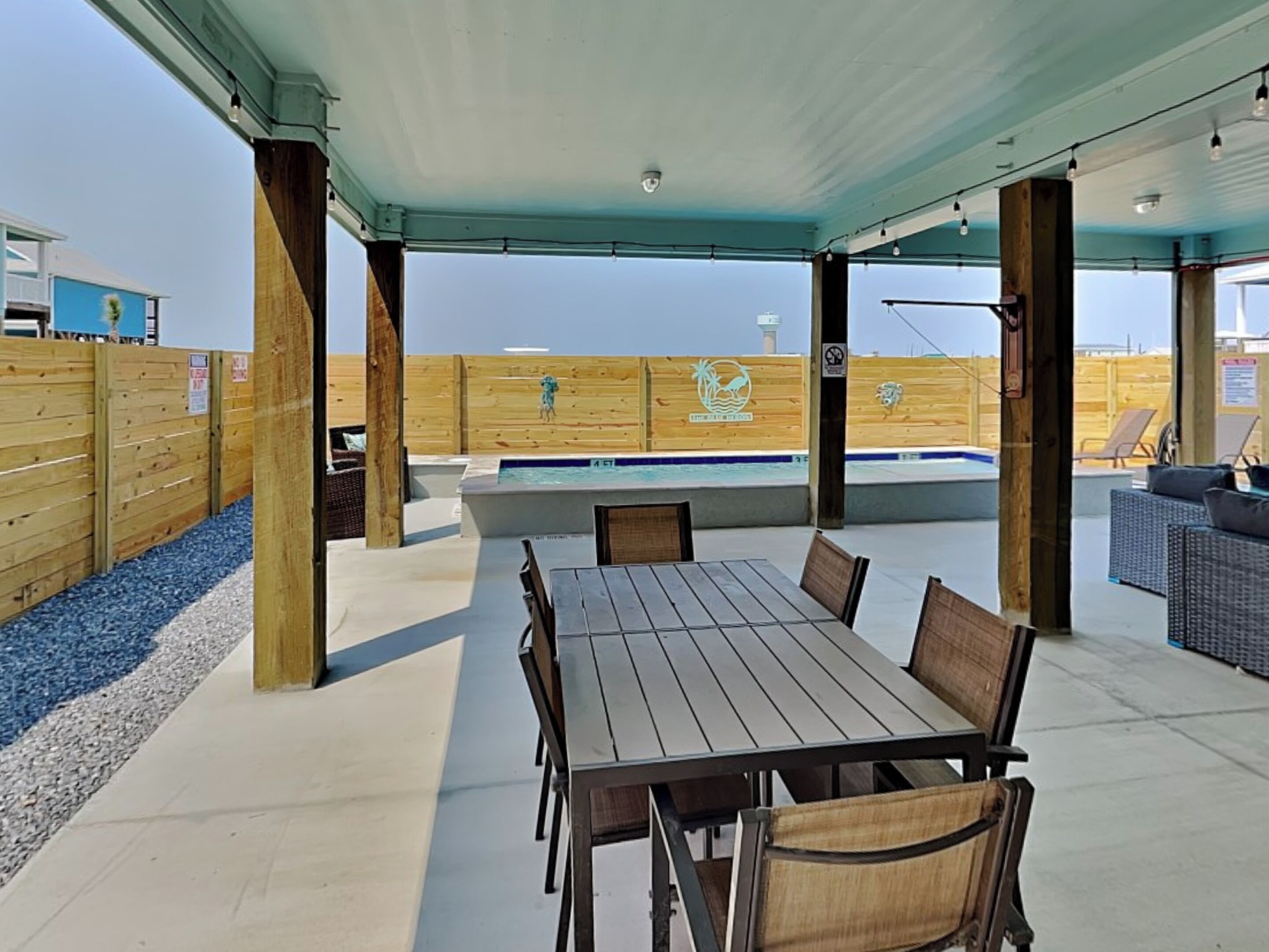 An outdoor patio with a pool, wooden deck, and seating area.