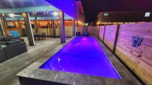 Uma área de piscina ao ar livre com um deck de madeira e um espaço de estar coberto.